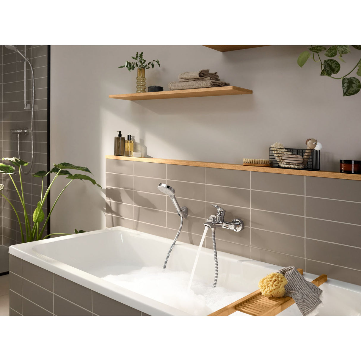 Mitigeur de baignoire Grohe, chrome, installé sur des carreaux taupe dans une salle de bain moderne