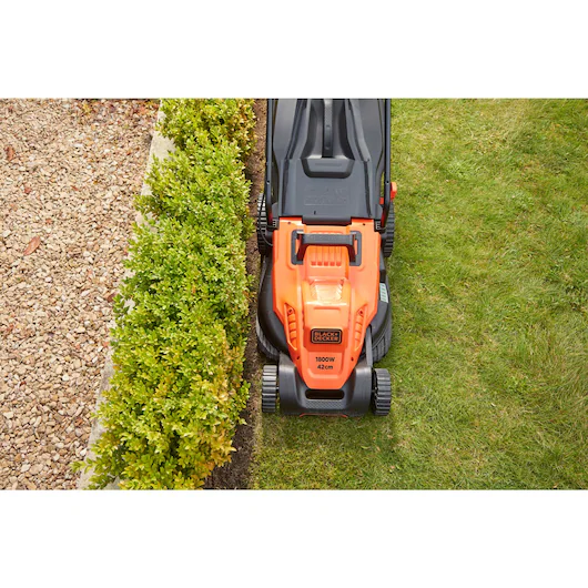 Tondeuse filaire BLACK+DECKER EASYSTEER de 42 cm avec moteur universel 1800 W, lame en action sur une pelouse.