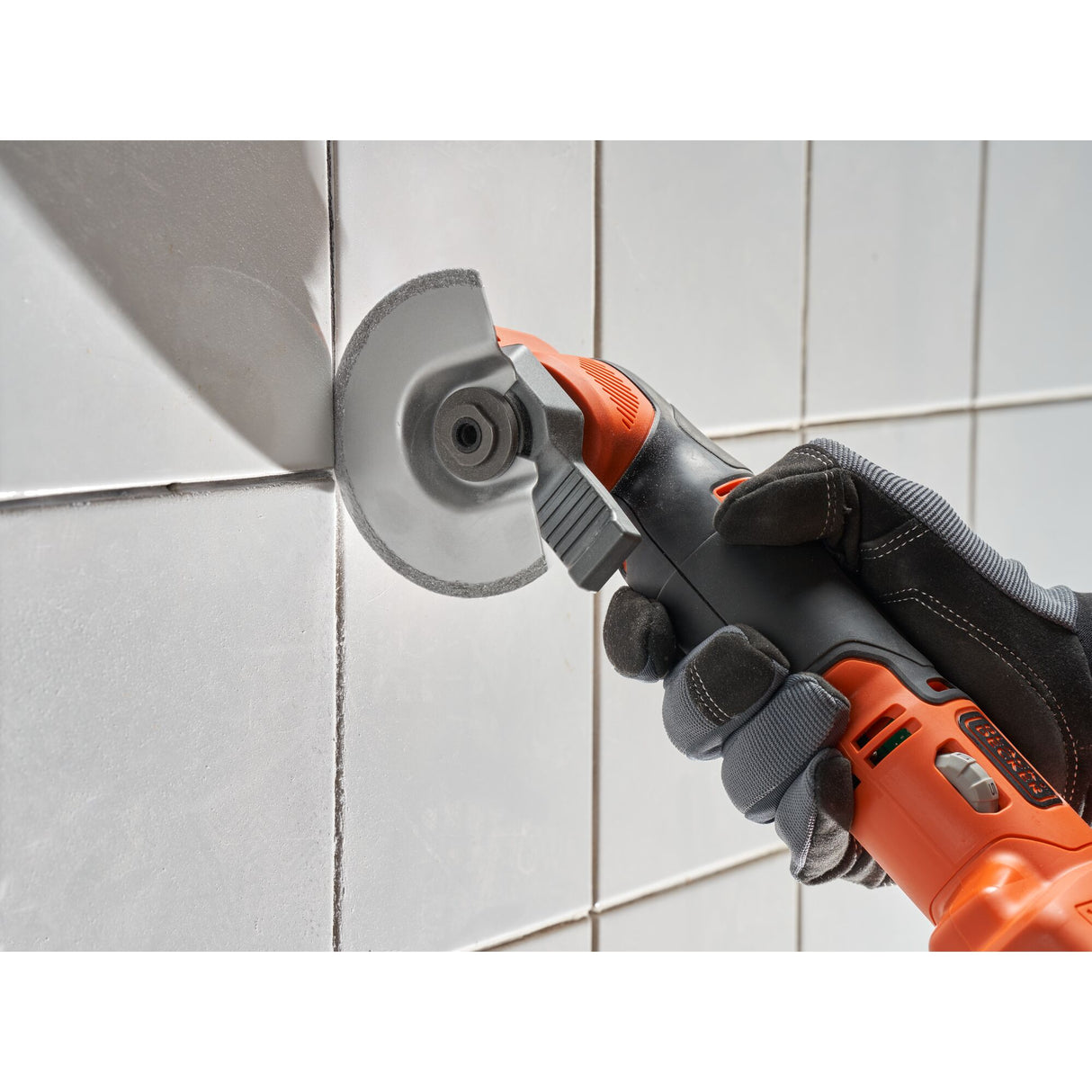 Meuleuse orange Fein, outil électrique de découpe, utilisée sur carrelage mural blanc.