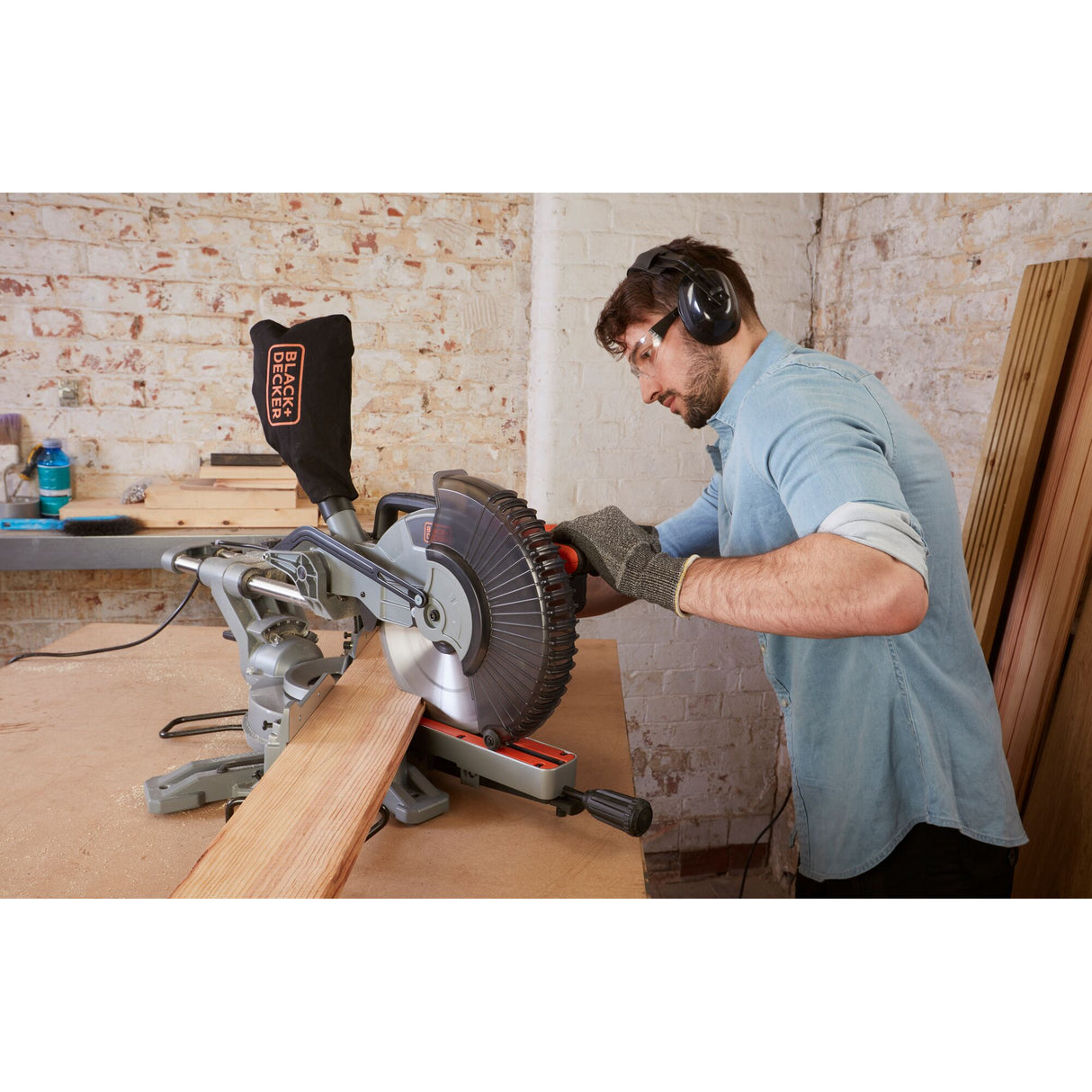 Scie à onglet noire Black+Decker, utilisée pour couper du bois, dans un atelier.