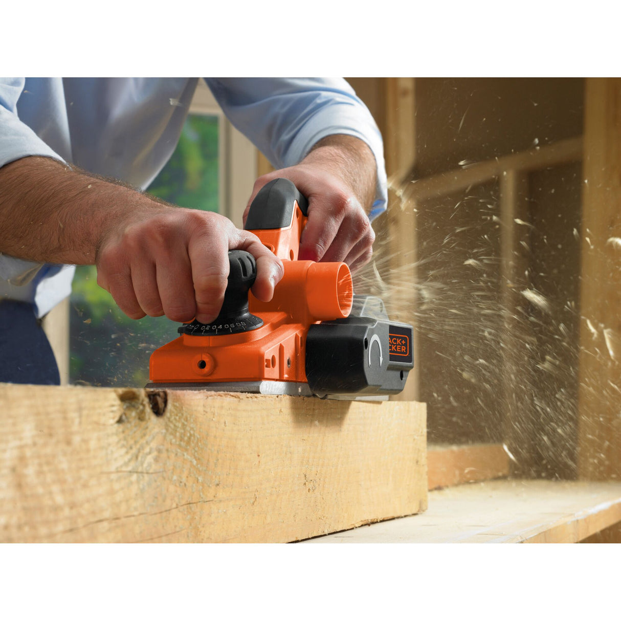 Rabot électrique Black+Decker orange utilisé sur une planche de bois, outil électroportatif