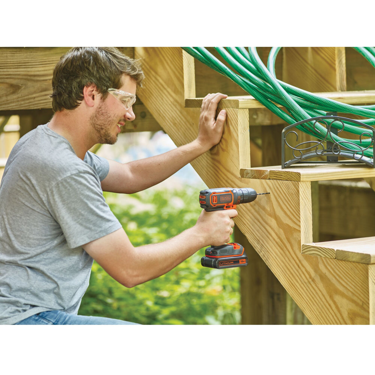 Perceuse visseuse Black & Decker, outil électroportatif, couleur noire et orange, en utilisation sur escalier en bois.