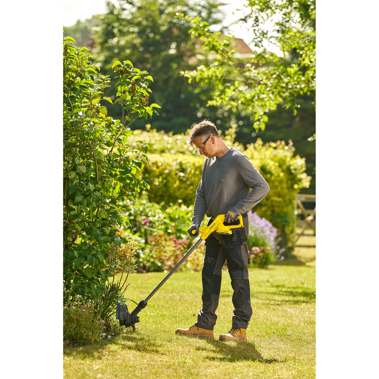 Homme utilisant un coupe-bordures Karcher jaune, outil de jardinage électrique, en plein air