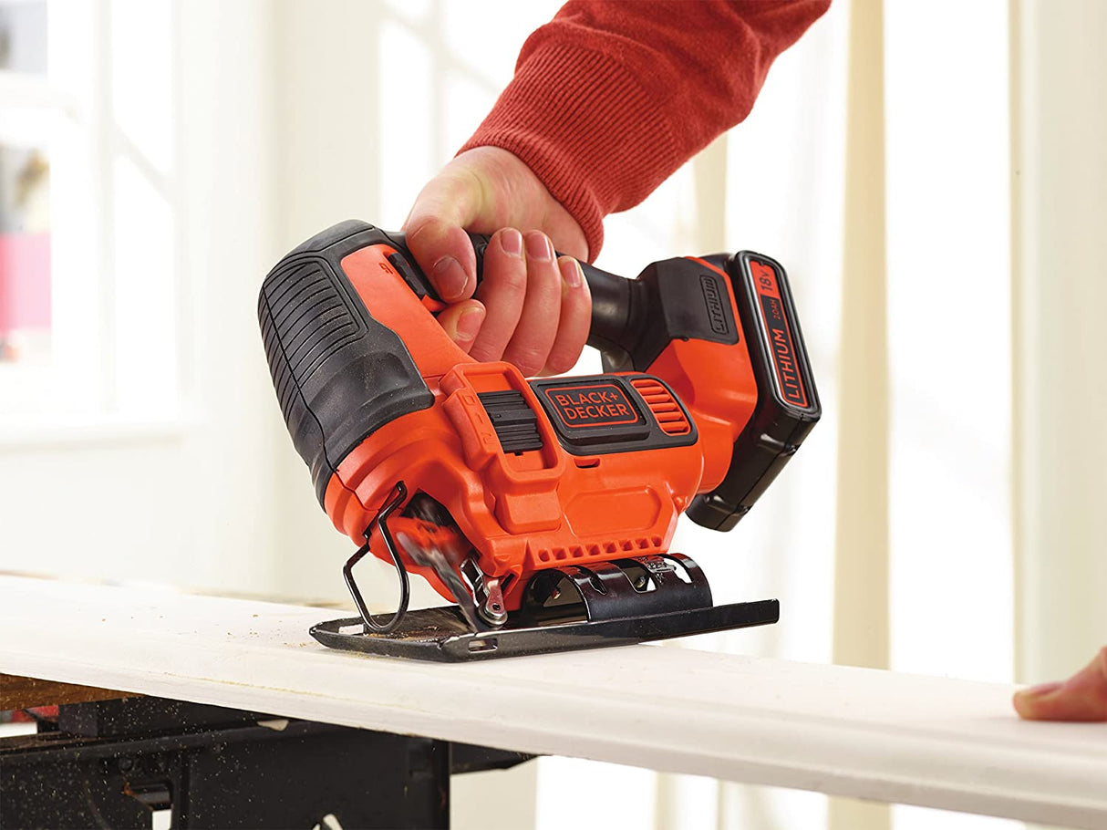 Scie sauteuse Black+Decker sans fil, couleur orange et noire, en cours d’utilisation sur du bois.