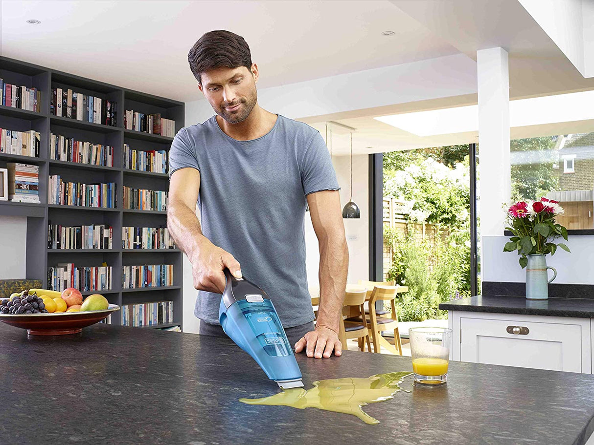 Aspirateur à main Black+Decker, bleu, utilisé pour nettoyer un liquide sur un plan de travail.
