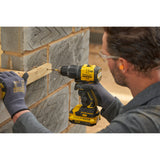 Perceuse-visseuse jaune Stanley, outil électroportatif, utilisée sur un mur en brique