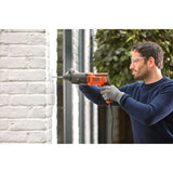Perceuse filaire Black+Decker orange et noire en utilisation sur mur blanc