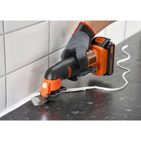 Outil multifonction Black+Decker, coupeur électrique orange et noir, utilisé pour enlever du joint.