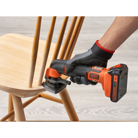 Ponceuse sans fil Black+Decker orange et noire utilisée sur une chaise en bois