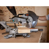 Scie à onglet grise Black+Decker utilisée pour couper du bois, outil électroportatif.