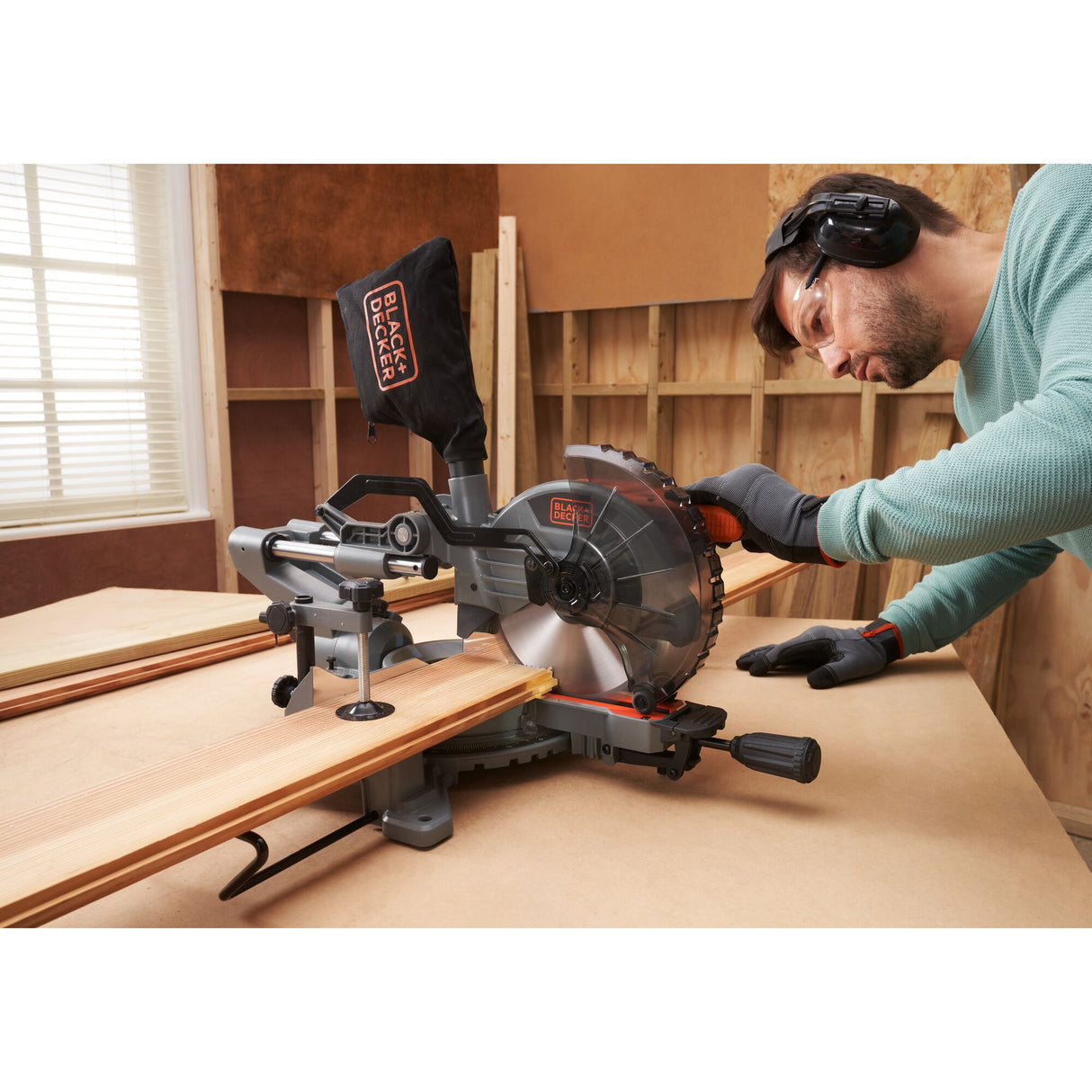 Scie à onglet noire et grise Black+Decker utilisée sur du bois, couleur noir/gris.