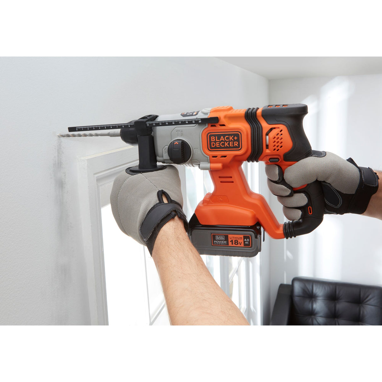 Perforateur sans fil Black+Decker, couleur orange et noir, en utilisation sur un mur.