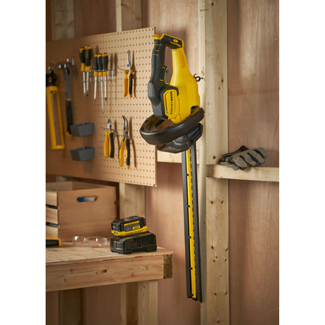 Taille-haie sans fil Stanley, couleur jaune et noir, suspendu dans un atelier.