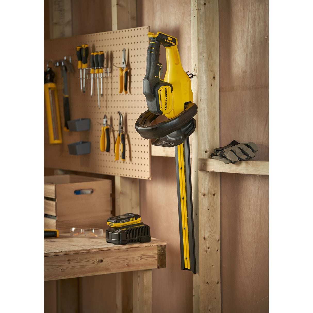 Taille-haie Stanley jaune et noir suspendu dans un atelier, outil électrique de jardinage.