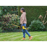 Femme utilisant un taille-haie jaune et noir de marque DeWalt dans un jardin