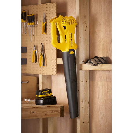 Souffleur sans fil Stanley jaune et noir, outil de jardinage accroché au mur.