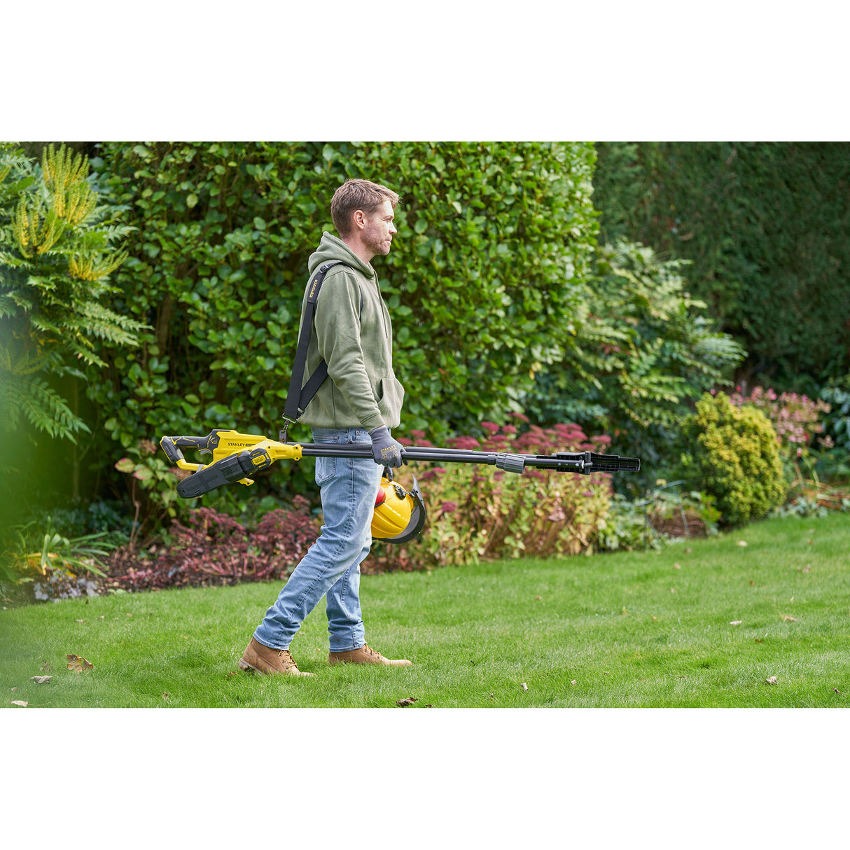 Homme portant une tronçonneuse élagueuse jaune Stanley, outil de jardinage électrique.