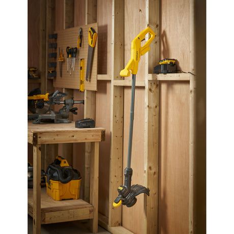 Coupe-bordures jaune Stanley, outil de jardin, couleur jaune et noir, dans un atelier bois.