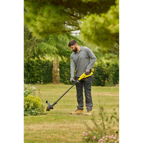 Homme utilisant un coupe-bordure jaune Dewalt pour gazon, outil de jardinage électrique.
