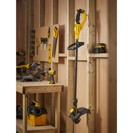 Coupe-bordures Stanley jaune et noir suspendu dans un atelier en bois, outil électroportatif.