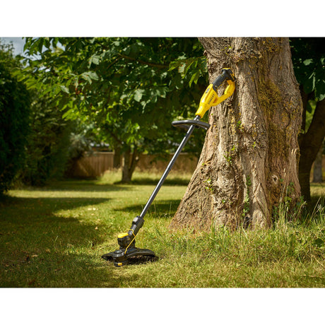 Coupe-bordure jaune Stanley, outil de jardinage électrique posé contre un arbre