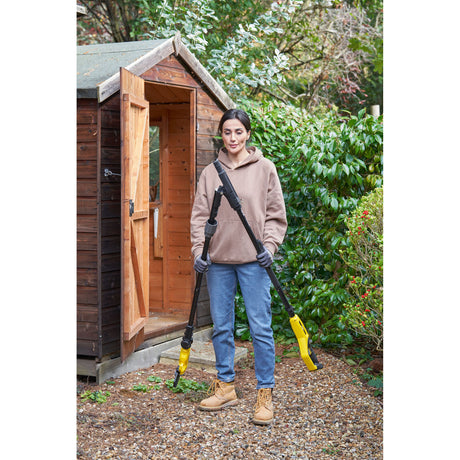 Femme tenant un désherbeur électrique Kärcher jaune pour jardin, outil de jardinage.