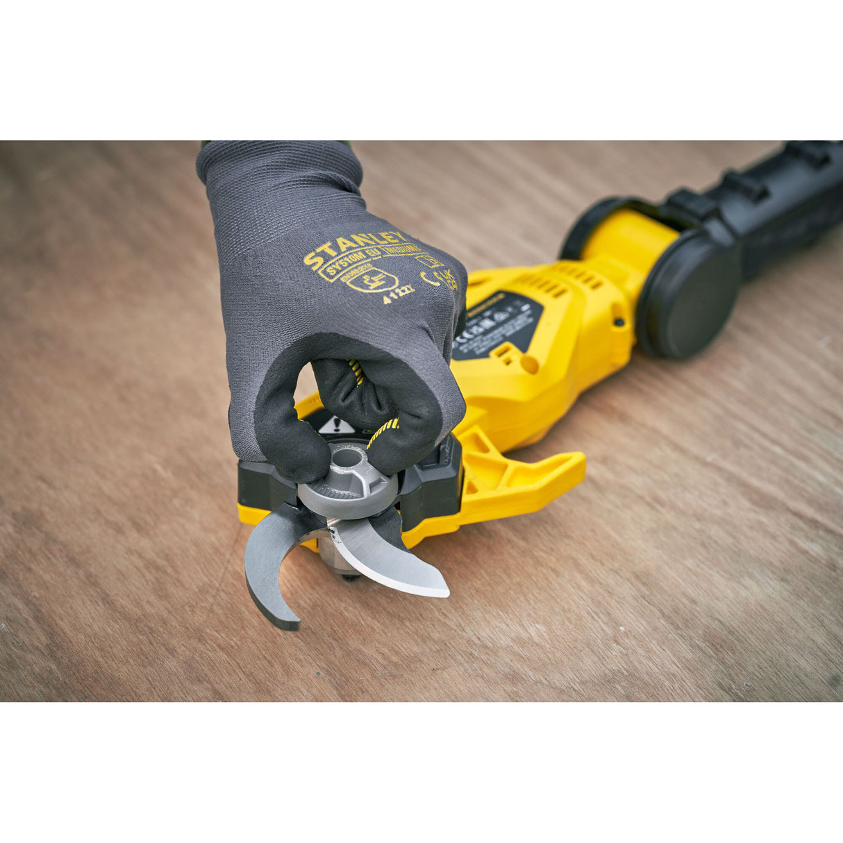 Sécateur électrique Stanley jaune, outil de coupe sur table en bois