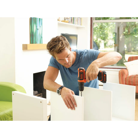 Perceuse-visseuse Black+Decker sans fil, couleur orange, utilisée pour monter un meuble