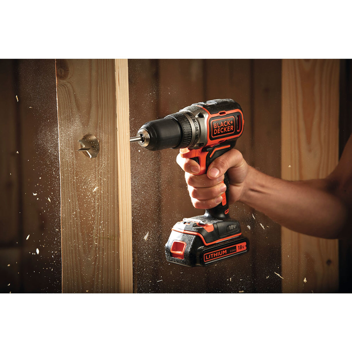 Perceuse visseuse sans fil noire et orange Black+Decker 18V en action sur bois