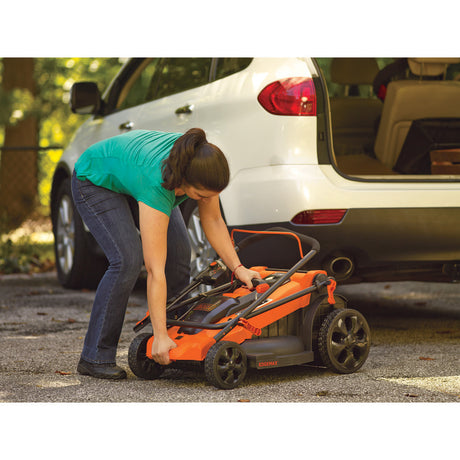 Tondeuse à gazon Black+Decker orange pliable, femme la range près d'une voiture blanche