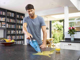 Aspirateur à main Black+Decker, bleu, utilisé pour nettoyer un liquide sur un plan de travail.