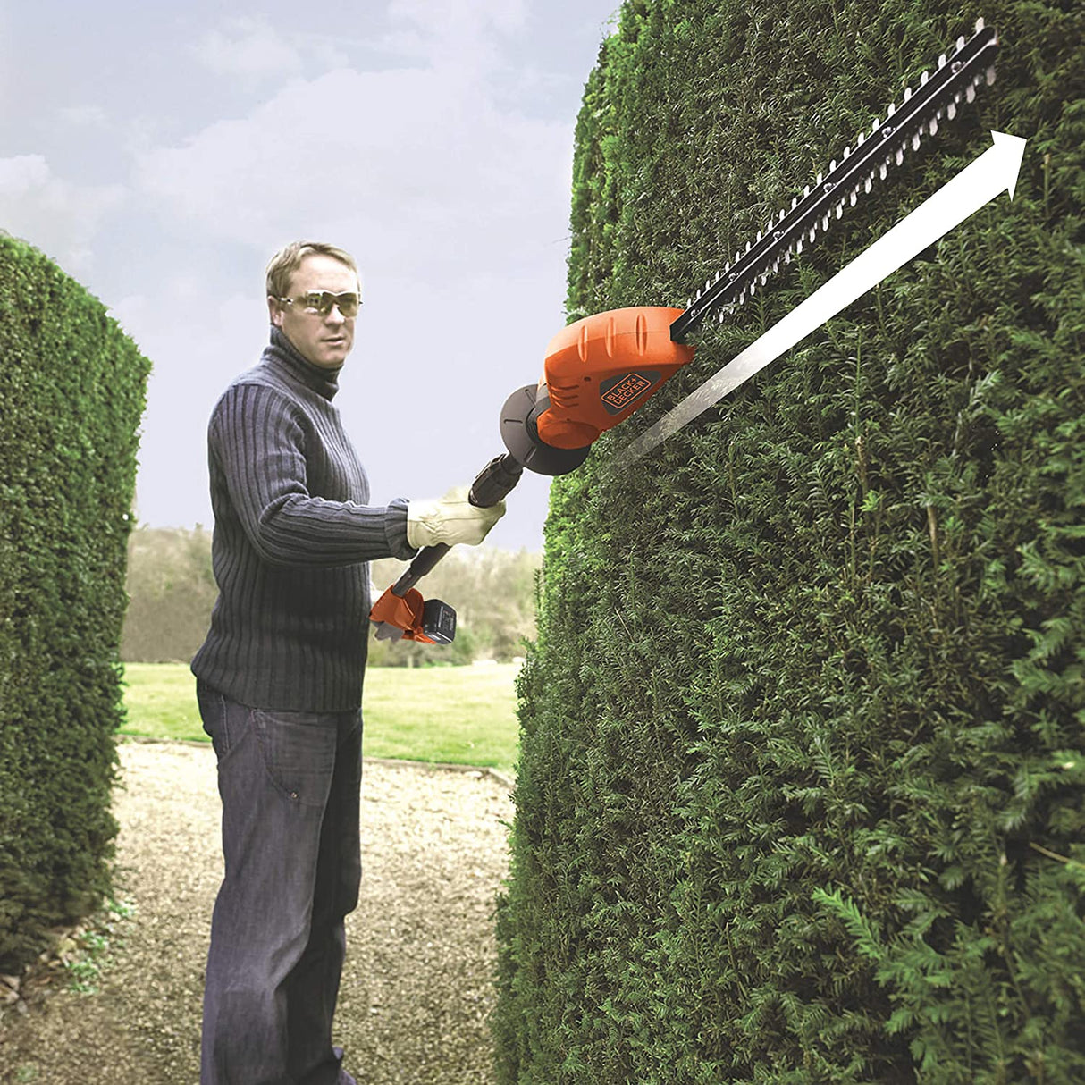 Taille-haie Black+Decker orange utilisé pour tailler une haie verte